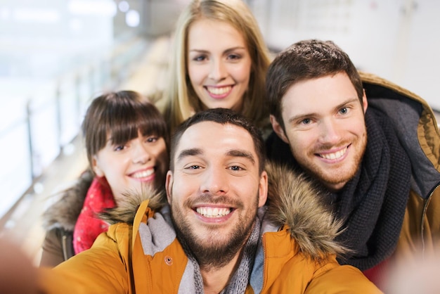 mensen, vriendschap, technologie en vrije tijd concept - gelukkige vrienden nemen selfie met camera of smartphone op ijsbaan