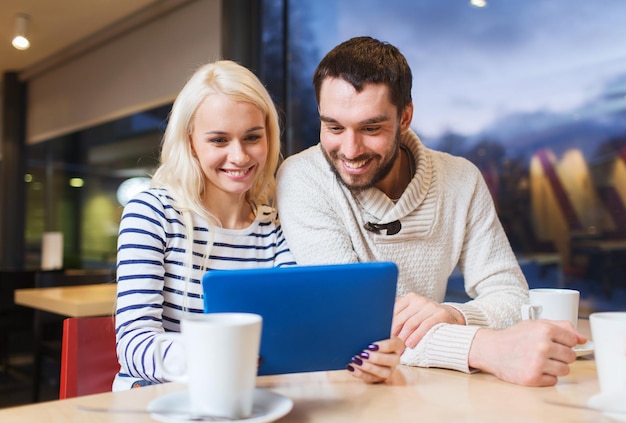 mensen, vrije tijd, communicatie, eten en drinken concept - gelukkig stel met tablet pc-computer die thee of koffie drinkt in café