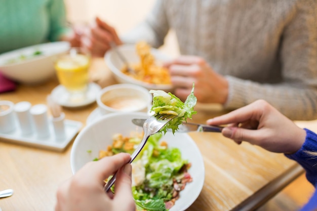 mensen, vrije tijd en eten concept - close-up vrienden die dineren en eten in restaurant
