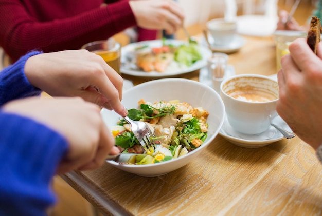 mensen, vrije tijd en eten concept - close-up vrienden die dineren en eten in restaurant