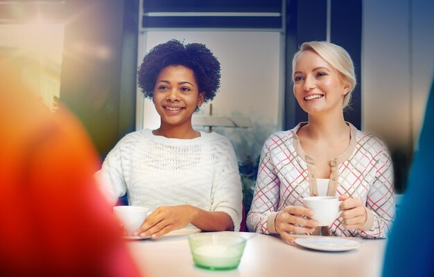 mensen vrije tijd vriendschap en communicatie concept gelukkige jonge vrouwen ontmoeten en drinken thee of koffie in een café