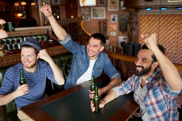 mensen, vrije tijd, vriendschap en vrijgezellenfeest concept - gelukkige mannelijke vrienden die gebotteld bier drinken en plezier hebben in de bar of pub