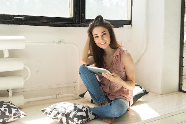 Foto mensen, werk en interieur concept - jonge vrouw die werkt door tablet in de woonkamer