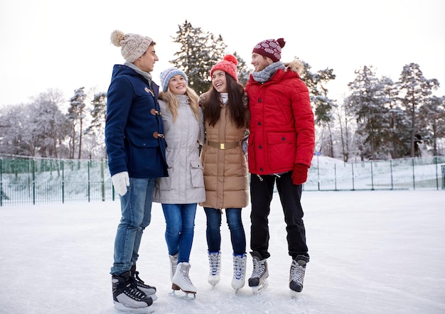 mensen, winter, vriendschap, sport en vrije tijd concept - gelukkige vrienden schaatsen en knuffelen op de ijsbaan buitenshuis