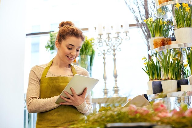 mensen, zaken, technologie, verkoop en bloemisterij en concept - gelukkige glimlachende bloemistenvrouw met de computer van tabletpc bij bloemenwinkel