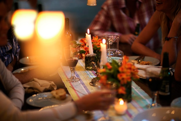 Mensen zitten aan een tafel met wijnglazen, borden met bloemen en kaarsen