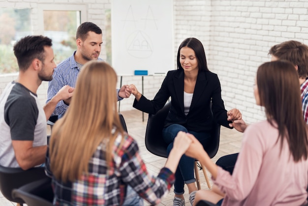 Mensen zitten en hand in hand tijdens therapiesessie.