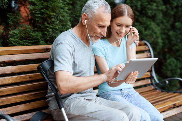 Mensen zitten op een bankje in het park met een tablet