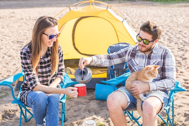 Mensen, zomertoerisme en natuurconcept - jong stel dat thee drinkt in de buurt van tent.