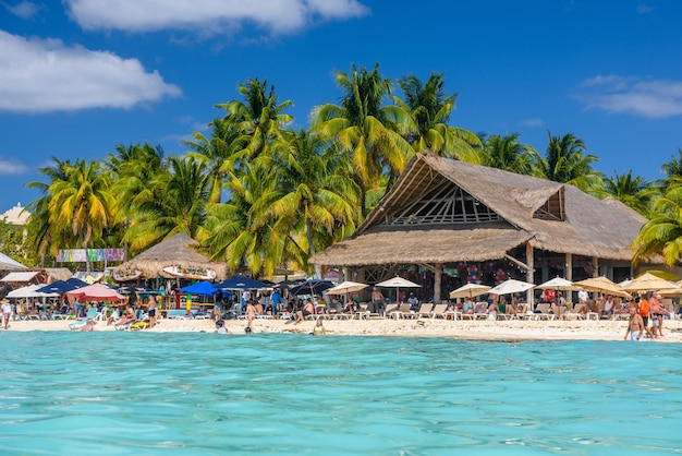 Mensen zonnebaden op het witte zandstrand met parasols bungalowbar en kokospalmen turquoise Caribische zee Isla Mujeres eiland Caribische Zee Cancun Yucatan Mexico