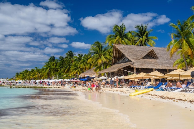 Mensen zonnebaden op het witte zandstrand met parasols bungalowbar en kokospalmen turquoise Caribische zee Isla Mujeres eiland Caribische Zee Cancun Yucatan Mexico