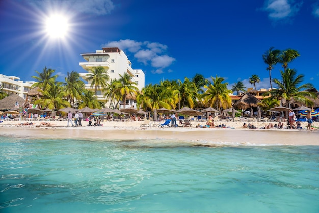 Mensen zonnebaden op het witte zandstrand met parasols bungalowbar en kokospalmen turquoise Caribische zee Isla Mujeres eiland Caribische Zee Cancun Yucatan Mexico