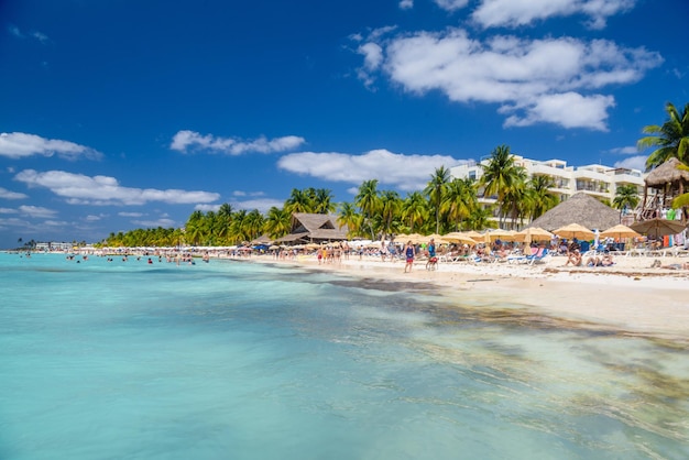 Mensen zwemmen in de buurt van wit zandstrand met parasols bungalowbar en kokospalmen turquoise Caribische zee Isla Mujeres eiland Caribische Zee Cancun Yucatan Mexico