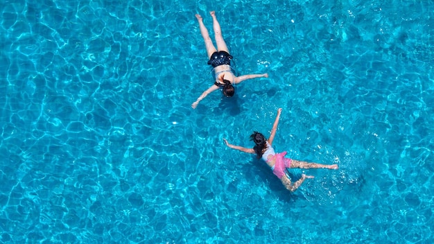 Mensen zwemmen in het hotelzwembad op vakantie zomerdag en spelen samen in familie en bovenaanzicht.