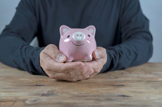 Mensenhand die geldmuntstuk in piggy steken om geldrijkdom te besparen
