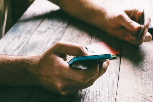 Foto mensenhanden die creditcard houden en mobiele telefoon in de avond met behulp van.