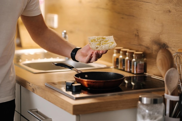 Mensenhanden leggen een sneetje stokbrood op de verwarmde pan Zelfgemaakt voedselconcept