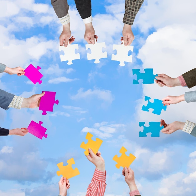 Foto mensenhanden met puzzelstukjes met witte wolken