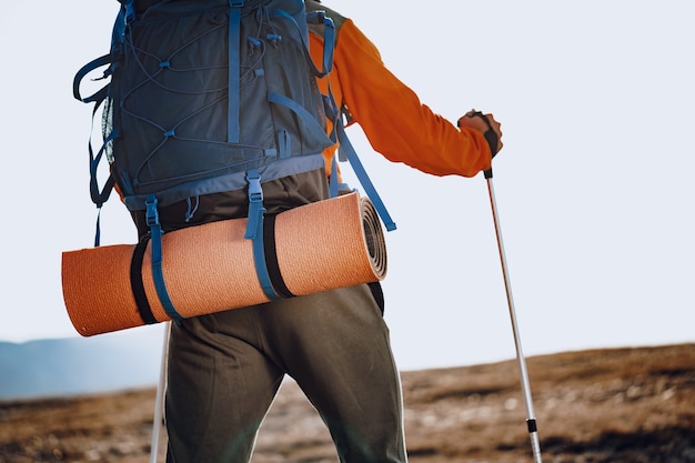 Mensenreiziger in sportkleding met wandelstokken die de berg opgaan