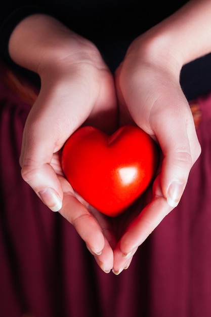 Mensenrelatie en liefdesconcept close-up van de tot een kom gevormde handen van de vrouw met rood hart
