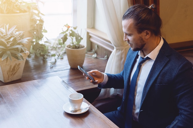 Mensenzitting in de koffiebar en het schrijven van een bericht op de mobiele telefoon tijdens koffiepauze.