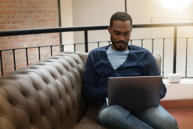 Mensenzitting op bank die aan computer in modern bureau werken