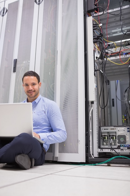 Foto mensenzitting op vloer die laptop met behulp van om servers te controleren