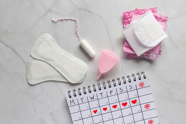 Menstrual calendar with sanitary napkins, tampons, menstrual cup.