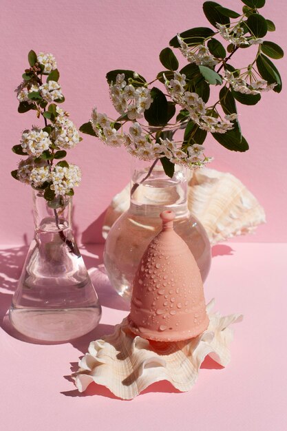 Menstrual cup ecofriendly reusable and silicone and flowers on a pink background