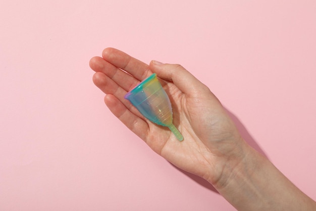 Menstrual cup in hand on pink background