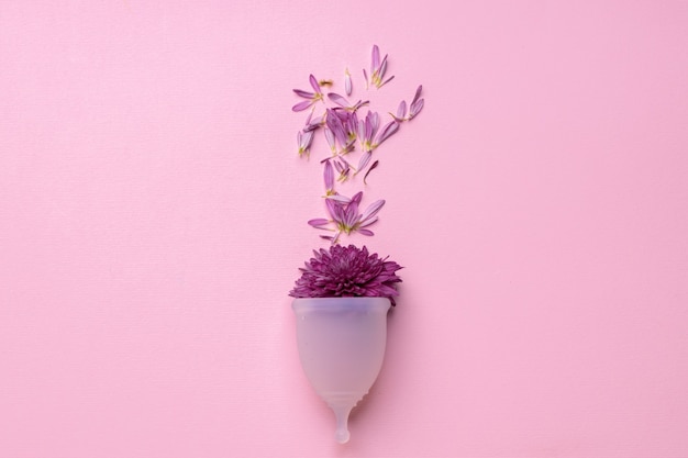 분홍색 배경에 꽃과 생리 컵