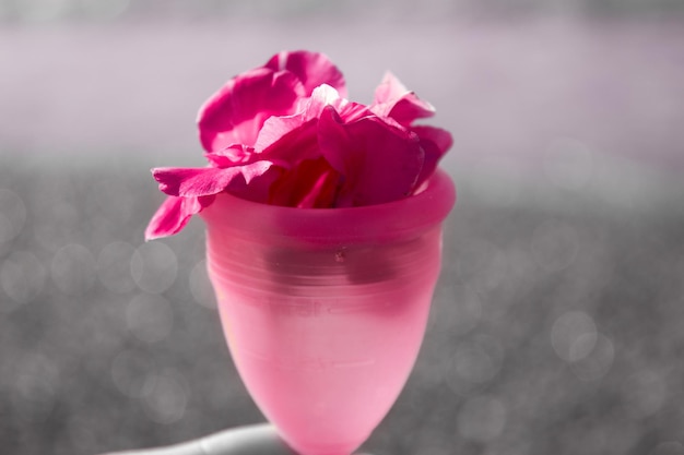 자기 관리의 바다 배경 개념 안에 분홍색 꽃이 있는 생리컵