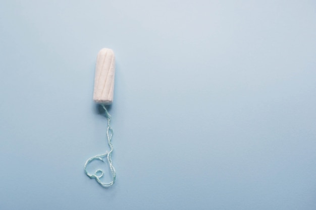 Menstrual tampon with heart on a blue background. Menstruation cycle. Hygiene and protection.