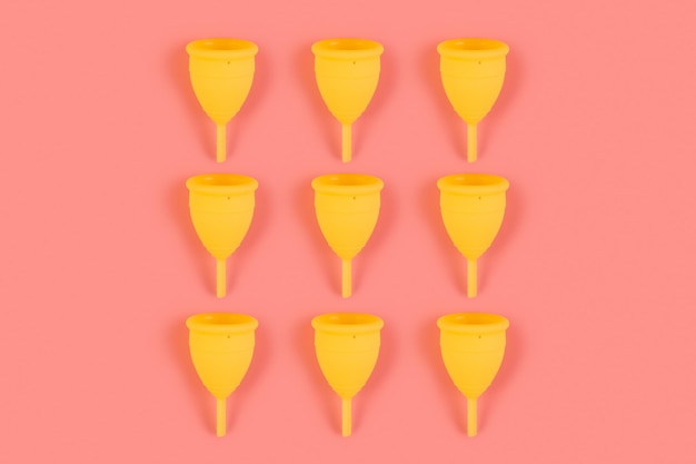 Menstrual yellow cups pattern on a pink background Monochrome zero waste concept ecofriendly