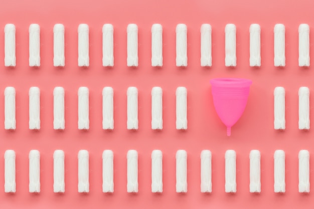 Menstruatie cup en tampons op roze achtergrond