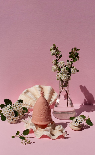 Menstruatiecup milieuvriendelijk herbruikbaar en siliconen en bloemen op een roze achtergrond