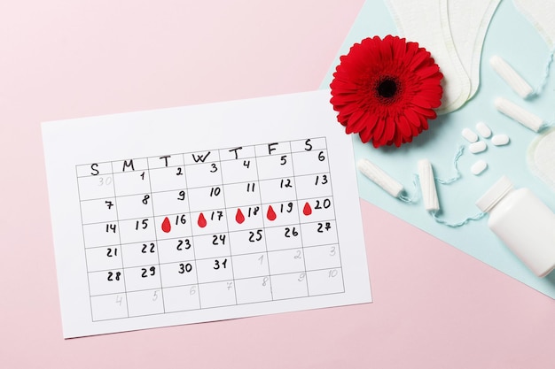 Menstruatiecycluskalender op een roze achtergrond. pillen en tampons, maandverband. ovulatie concept. menstruatie concept.