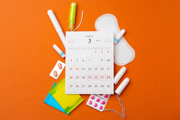 Menstruatiekalender met maandverband en tampons, pillen bovenaanzicht
