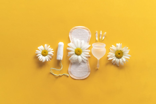 Menstruatieperiode concept Hygiënische witte vrouwelijke pad Menstruatiecup en tampon met kamille bloemen Menstruatiebescherming Gezondheid van vrouwen