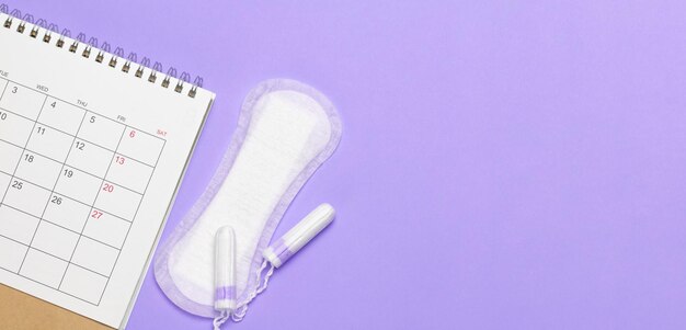 Menstruation calendar Calendar with pads and tampons on a purple background Template Copy space for text mockup