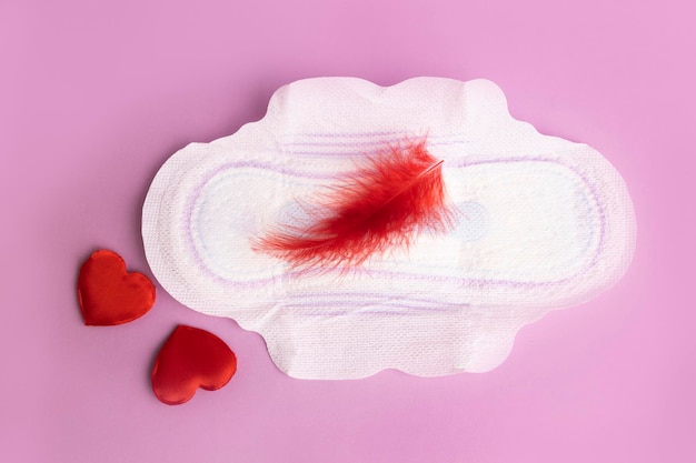 Photo menstruation calendar concept with sanitary pads and feather