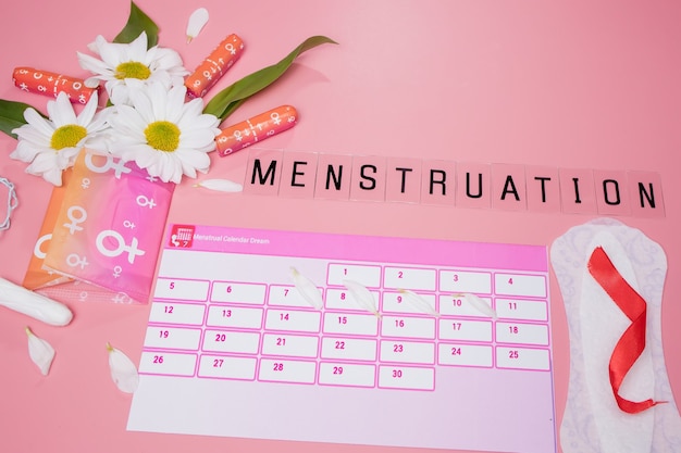 Foto calendario delle mestruazioni con tamponi di cotone, assorbenti, fiore bianco. giorni critici per la donna, protezione dell'igiene della donna