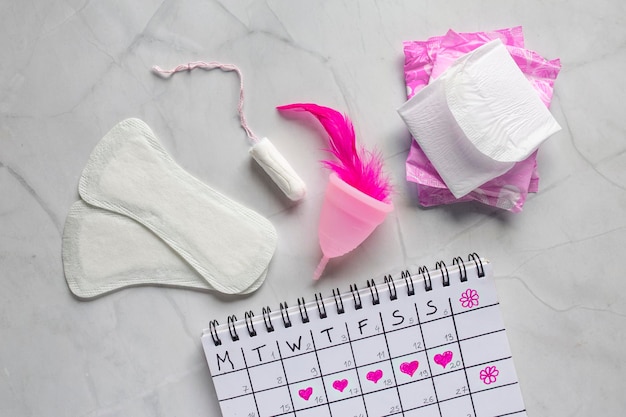 Photo menstruation calendar with cotton tampons woman hygiene protection woman critical days set of womens means personal hygiene feminine hygiene pads cup menstruation