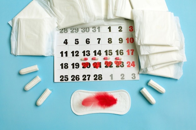 Photo menstruation cycle concept. menstruation calendar with sanitary pads, contraceptive pills, tampons