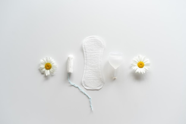 Menstruation period concept Hygienic white female pad Menstrual cup and tampon with chamomile flowers Menstruation protection Women's health