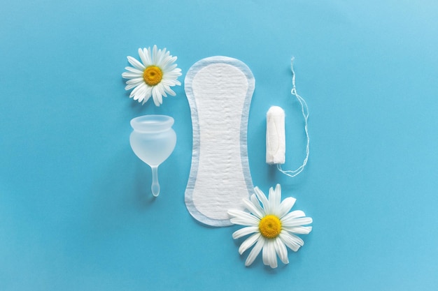 Menstruation period concept Hygienic white female pad Menstrual cup and tampon with chamomile flowers Menstruation protection Women's health