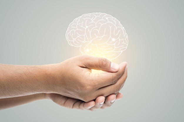 Mental health day. Man holding brain illustration on gray wall