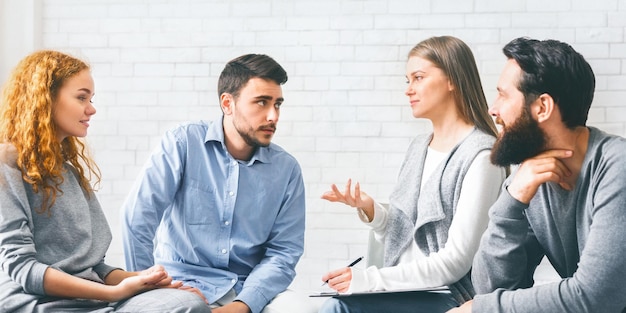 Mentor psychologist talking to group members at therapy session