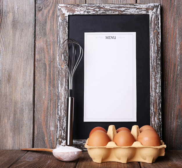 Menu board with eggs on rustic wooden planks background