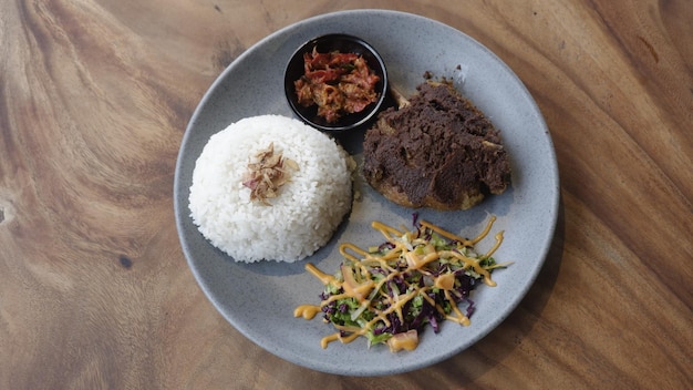 The menu of fried duck with ireng seasoning with salad and\
rice. indonesian special food. top view.